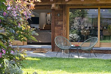 Two chairs and a table in front of a wooden house