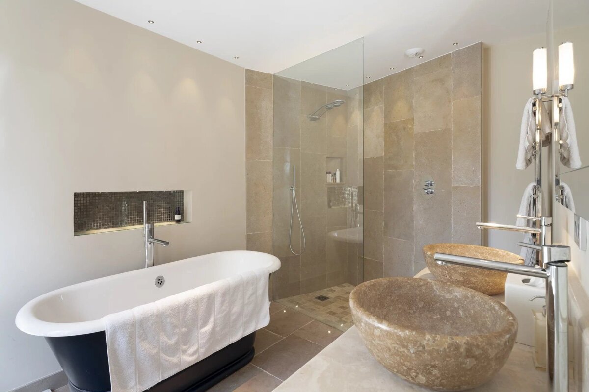 Elegant modern bathroom featuring a freestanding tub, glass walk-in shower, and double stone vessel sinks.