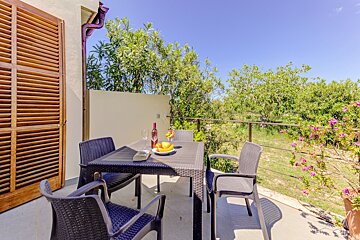 A patio with a table and chairs and a bottle of wine