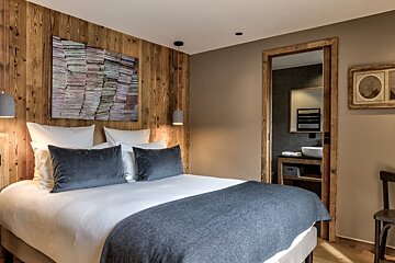 A bedroom with a painting on the wall above the bed