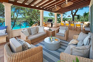 A patio with wicker furniture and a table with a bottle of wine on it