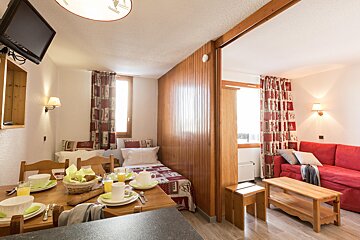 A living room with a red couch and a bed
