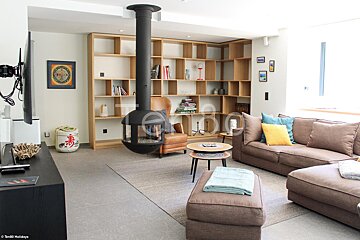 A living room with a couch a chair and a fireplace with the word holidays in the corner