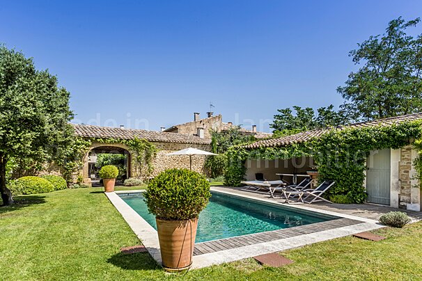 A large swimming pool is surrounded by a lush green lawn