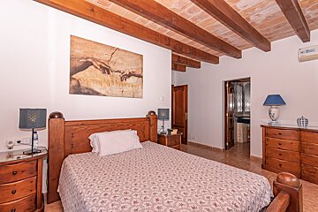 A bedroom with a painting on the wall above the bed