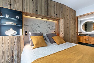 A bedroom with a bed and a painting of mountains on the wall
