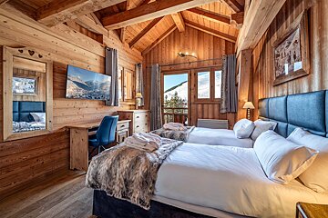 A bedroom with two beds and a flat screen tv