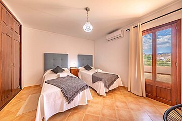 A bedroom with two twin beds and a balcony