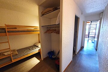 A closet with bunk beds and clothes hanging on it