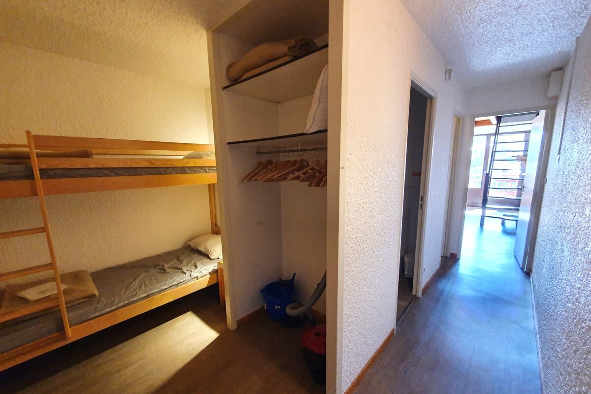 A closet with bunk beds and clothes hanging on it