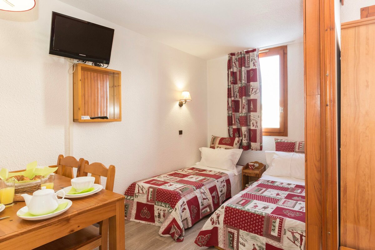 A bedroom with two beds and a flat screen tv