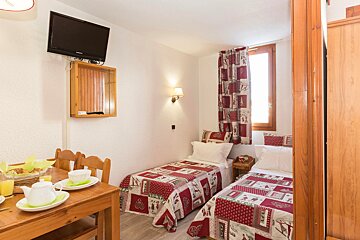 A bedroom with two beds and a flat screen tv