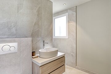 A bathroom with a round sink and a window