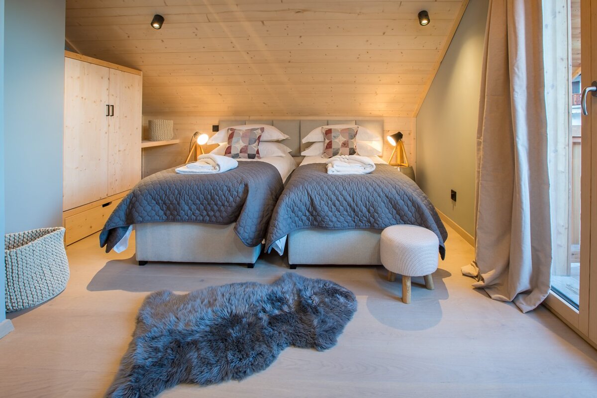 A bedroom with two beds and a rug on the floor