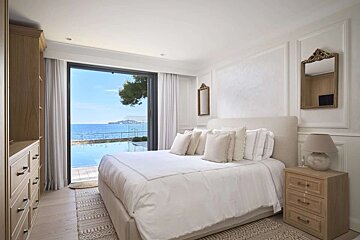 A bedroom with a large bed and a view of the ocean
