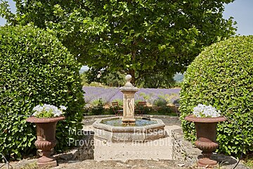 A fountain in the middle of a garden with the words made in provence on the bottom