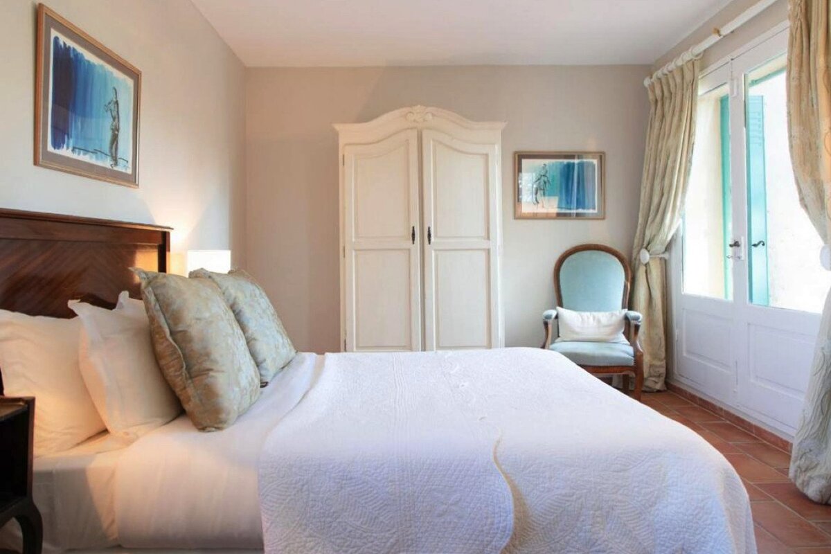 A bedroom with a large bed and a chair