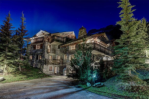 A large house with a lot of windows is lit up at night