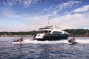 A group of people are riding jet skis next to a large yacht