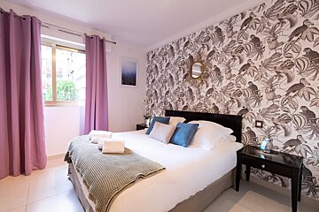 A bedroom with a large bed and purple curtains