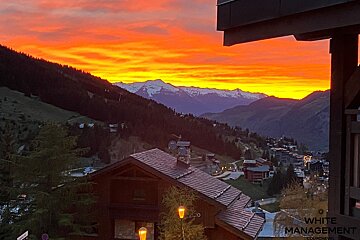 A sunset over a mountain village with a sign that says no parking