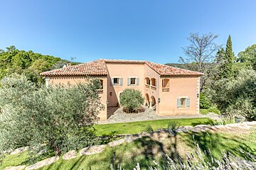 A large house with a red tile roof and white shutters