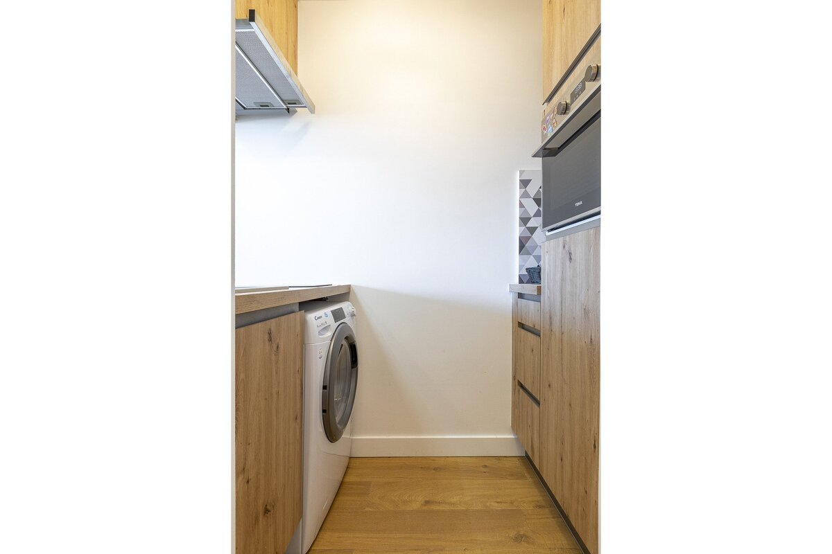 A kitchen with a washing machine and a microwave