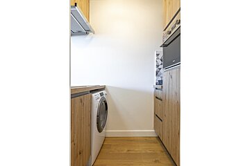 A kitchen with a washing machine and a microwave