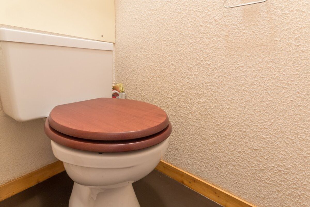 A toilet with a wooden seat in a bathroom