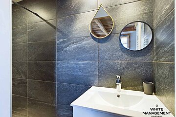 A bathroom with a sink and two mirrors and the words white management on the bottom