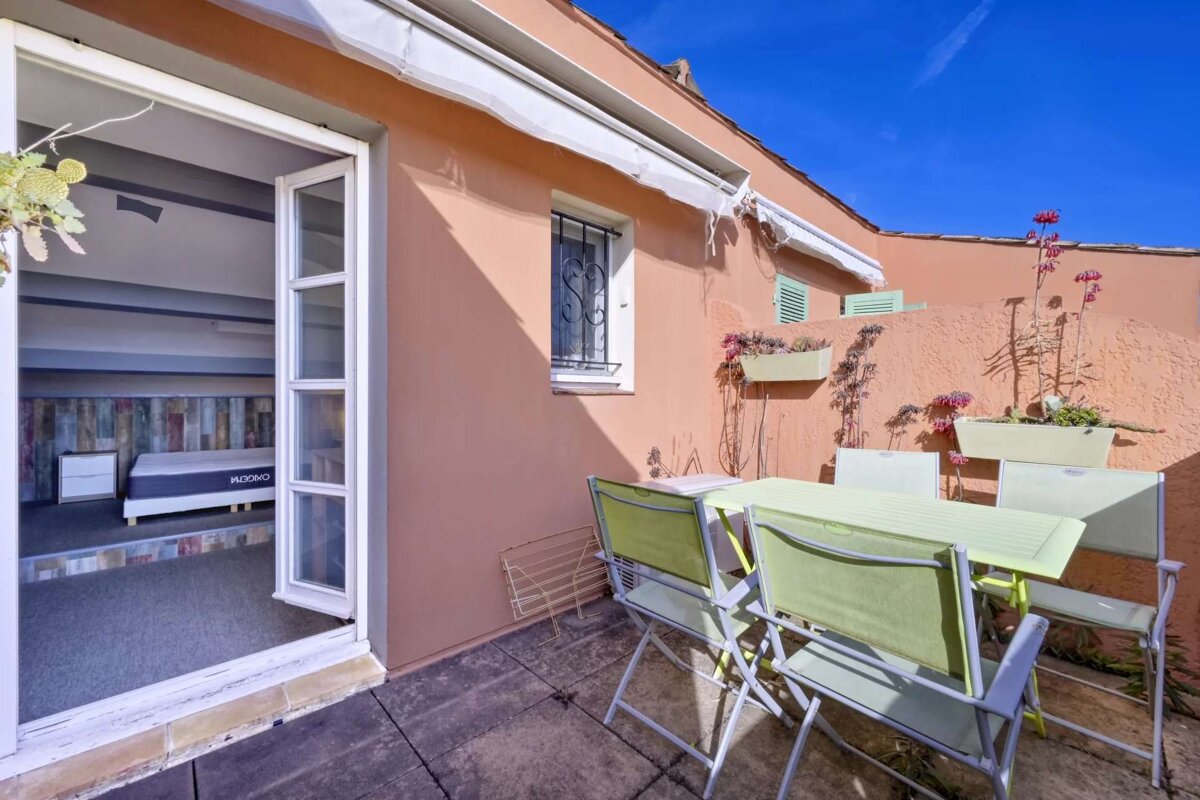 A patio with a table and chairs and a mattress in the background