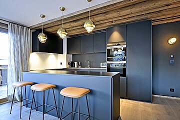 A kitchen with black cabinets and brown stools
