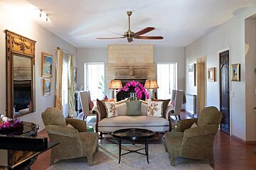 A living room with a couch and chairs and a ceiling fan