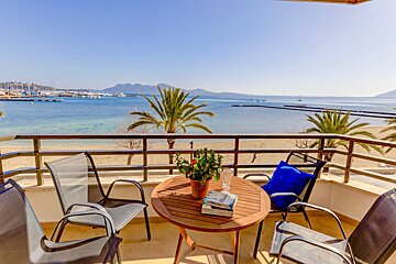 A table with a book on it sits on a balcony overlooking the ocean