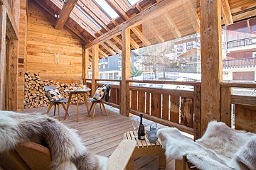 A wooden deck with a table and chairs and a bottle of wine