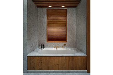 A bathroom with a tub and a window with wooden blinds