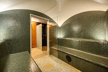 A bathroom with green tiles and a glass door