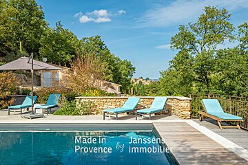 A large swimming pool is surrounded by chairs and umbrellas and says made in provence by immobilier
