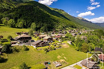 An aerial view of a mountain village with alpine property written in the corner
