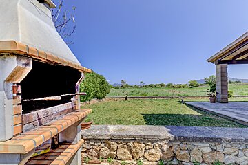 A brick bbq is sitting in the middle of a lush green field