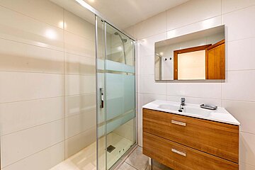A bathroom with a sliding glass shower door and a sink
