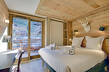 A bedroom with a bed and a deer head on the wall