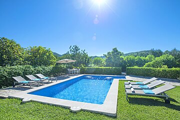 A large swimming pool surrounded by chairs and an umbrella