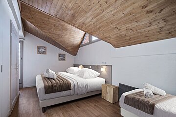 A bedroom with a wooden ceiling and two beds