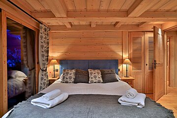 A bedroom with a wooden ceiling and a bed