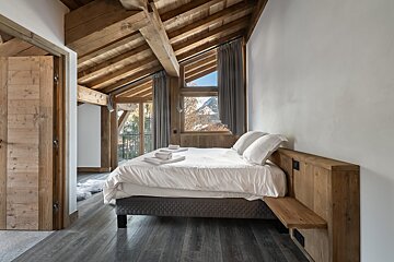 A bedroom with a large bed and a wooden ceiling