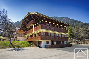 A large house with a yellow arrow pointing to the balcony
