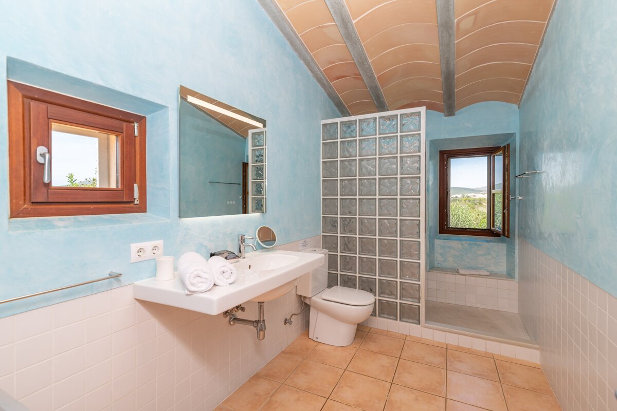 A bathroom with a sink toilet and a window