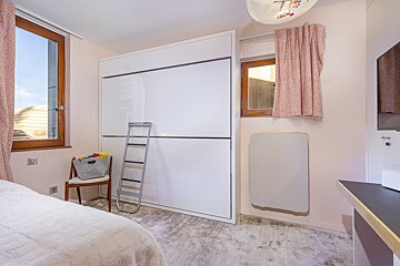 A bedroom with a bed and a ladder in it
