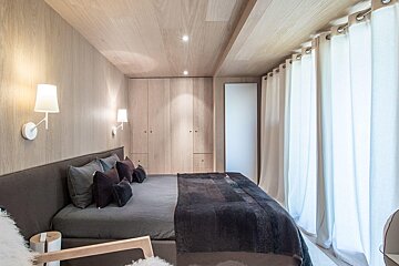 A bedroom with a bed and two lights on the wall